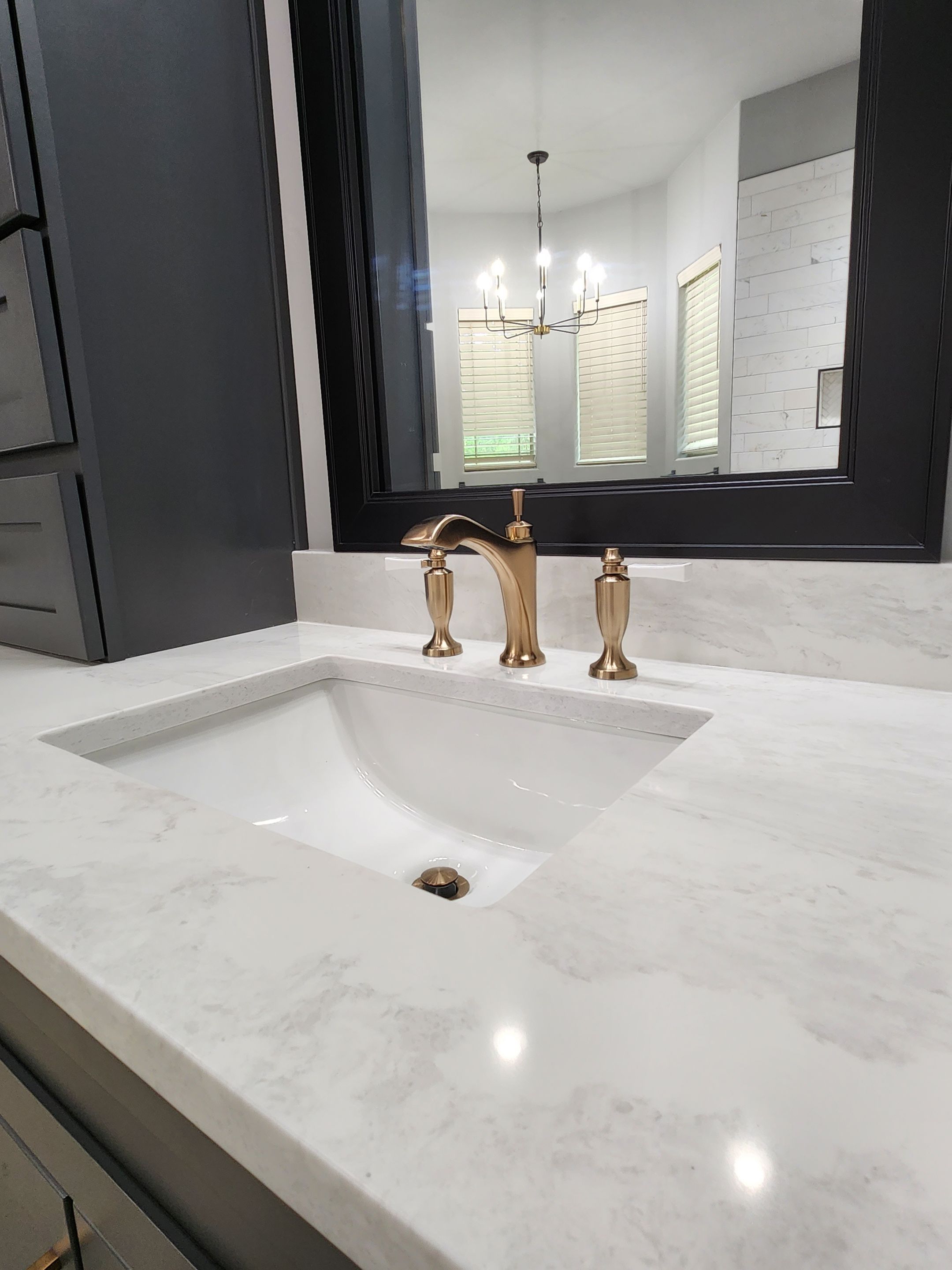 bathroom sink with gold faucet and light counter tops