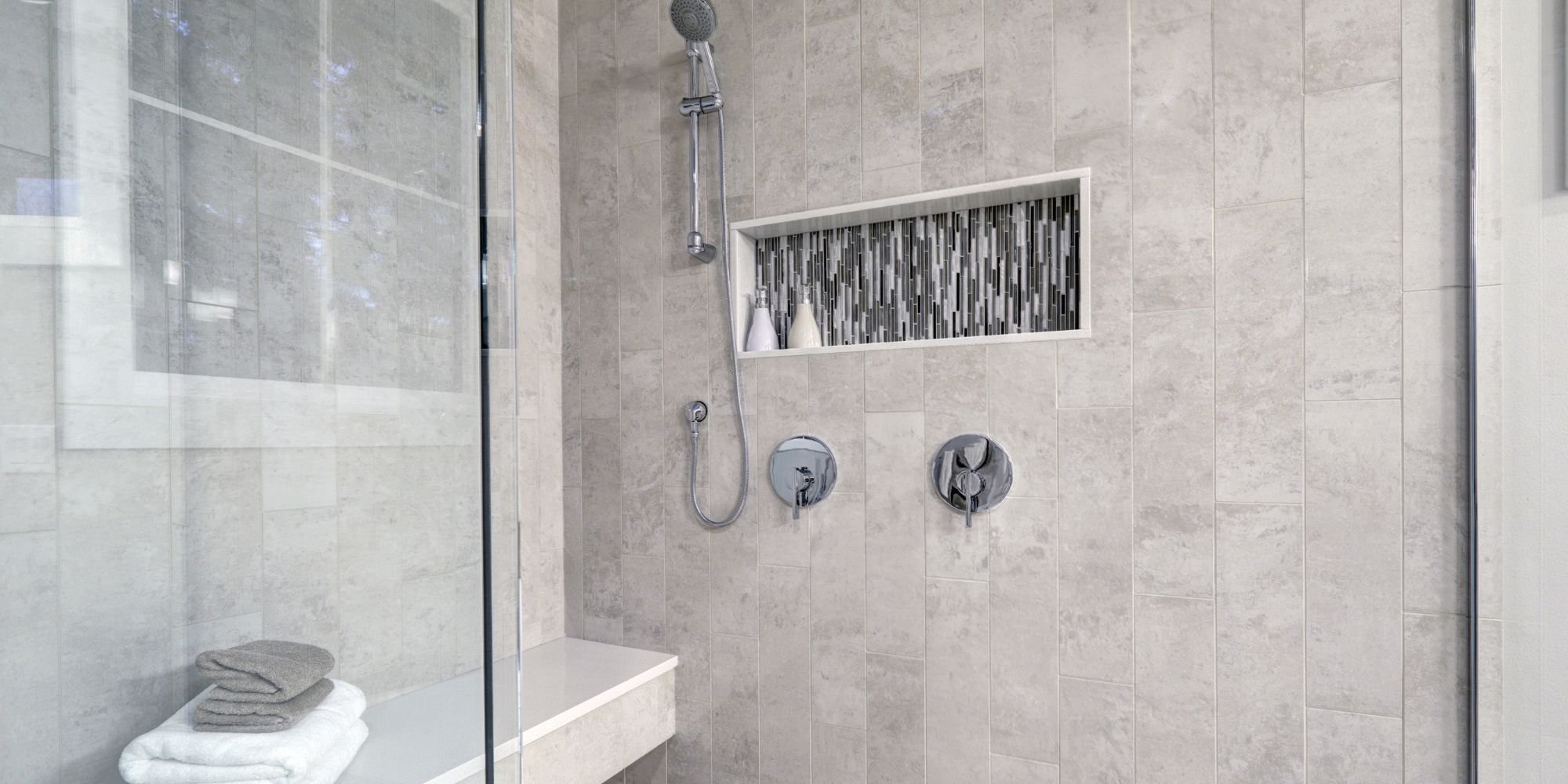 large walk in shower remodel with in shower bench and neutral stone tile